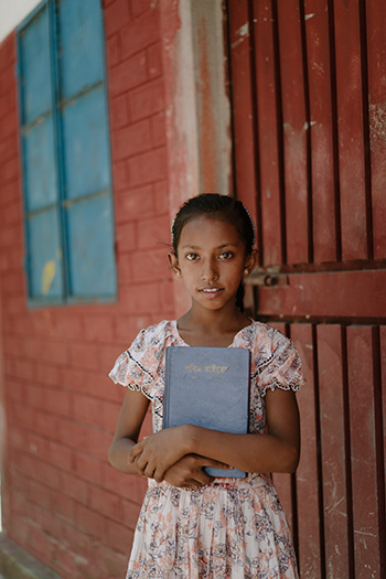 Rumana, a 9 year old girl in Bangladesh, holds a Bible 