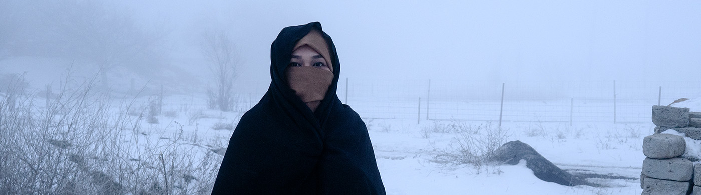 A woman in Islamic garb stands in a snowy scene